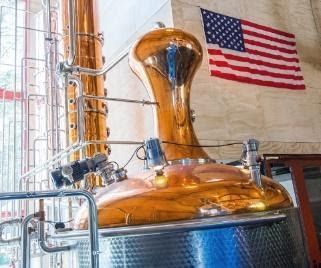 A large copper distillery with an american flag hanging from the wall.