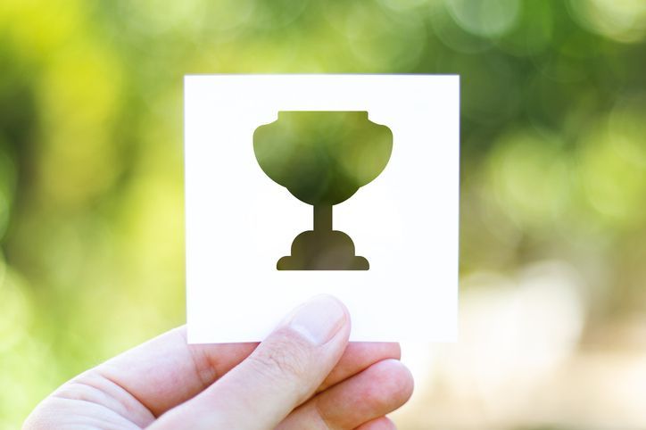 A person is holding a piece of paper with a trophy on it.