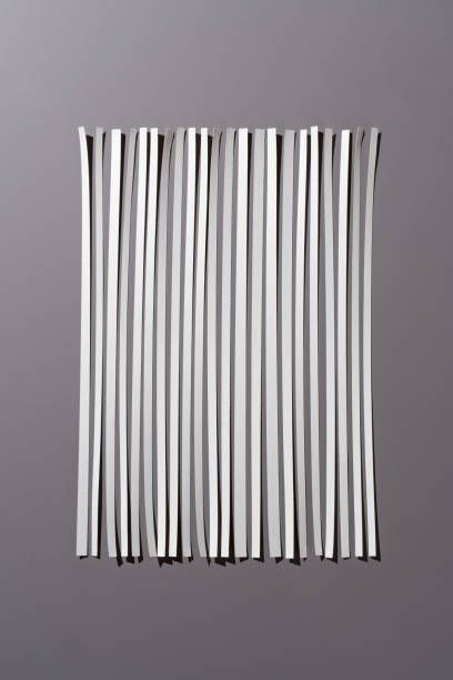 A row of white straws are stacked on top of each other on a gray surface.