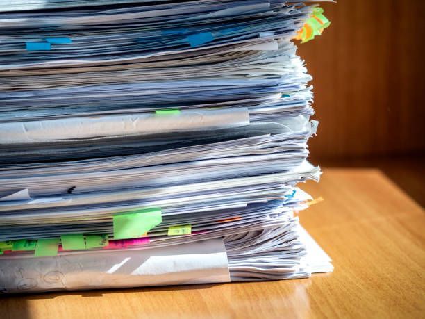 A stack of papers is sitting on a wooden table.