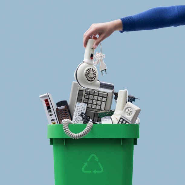 A person is putting a phone in a green recycling bin