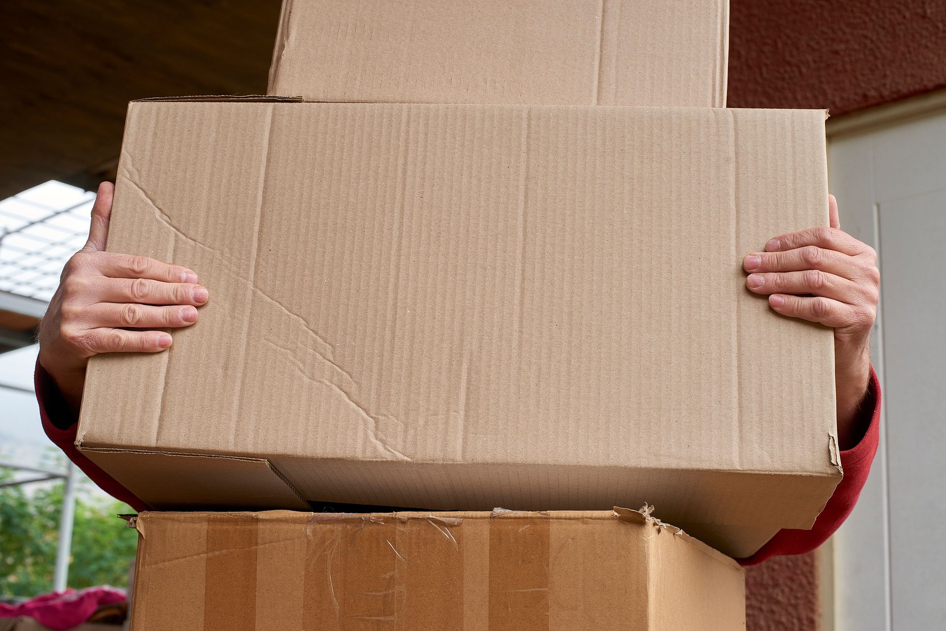 A person is holding a stack of cardboard boxes in their hands.