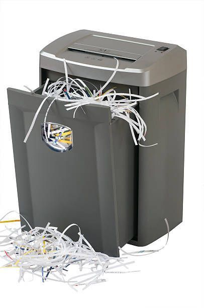 A paper shredder with shredded paper coming out of it.