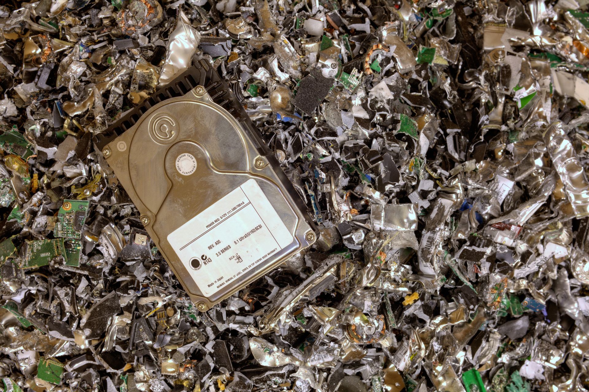 A hard drive is sitting on top of a pile of shredded plastic.