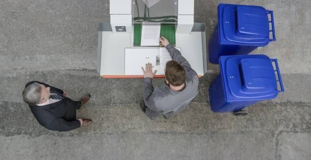 Two men are standing next to each other in front of a machine.