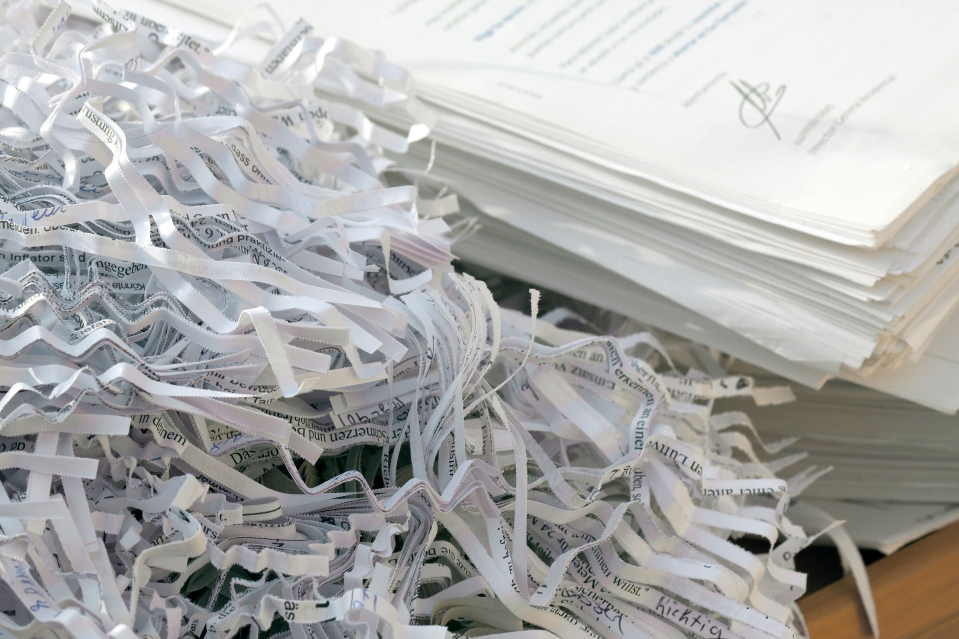 A pile of shredded paper next to a stack of papers