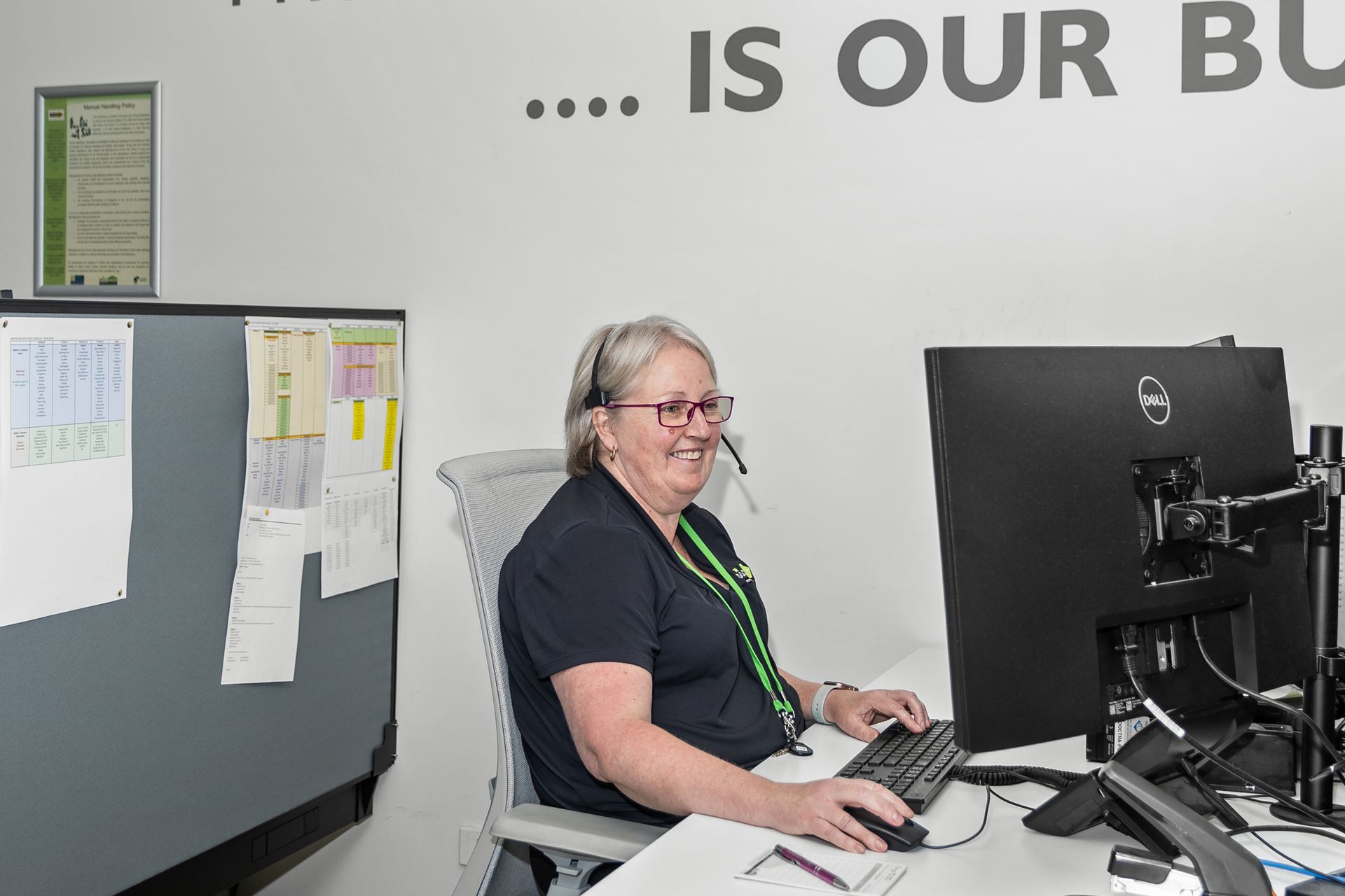 A woman is reaching for a binder on a shelf in a library.