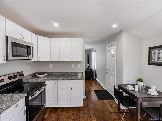 Kitchen with white cabinets, stainless steel appliances, granite countertops, and dark wood flooring.