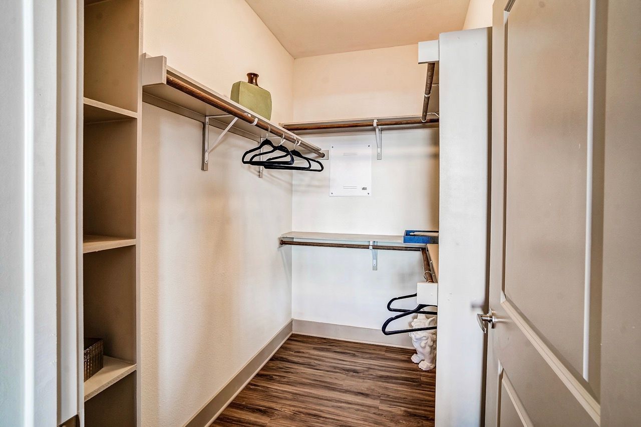 Walk-in closet with shelves and dual hanging rods, wood-look flooring.