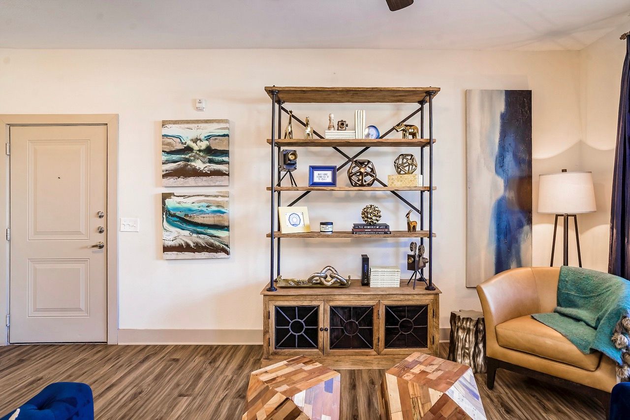 Living room with a tall wood-and-metal bookshelf, wall art, and a tan leather chair.