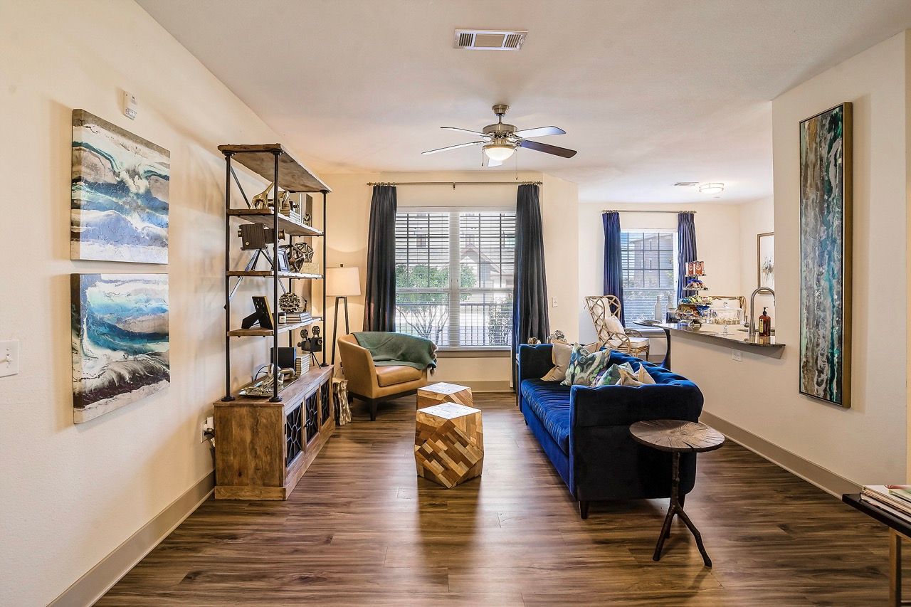 Living room with blue sofa, wooden floor, and large windows.