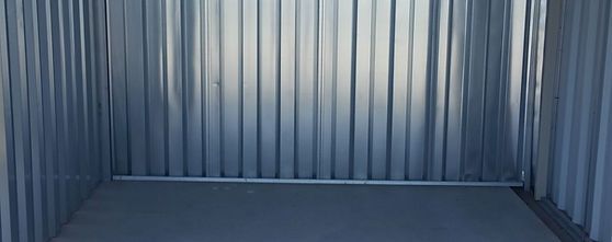 Empty room with a metal wall and concrete floor, suitable for industrial storage.