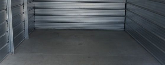 Small empty room with a concrete floor and metal walls, suitable for storage.
