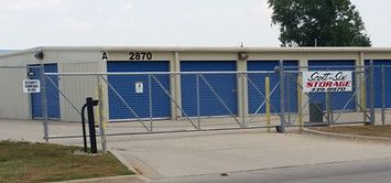 A storage facility with blue doors and a fence.