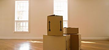 A bunch of cardboard boxes are stacked on top of each other in an empty room.