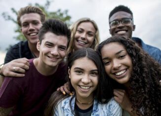 A group of young people are posing for a picture together and smiling.
