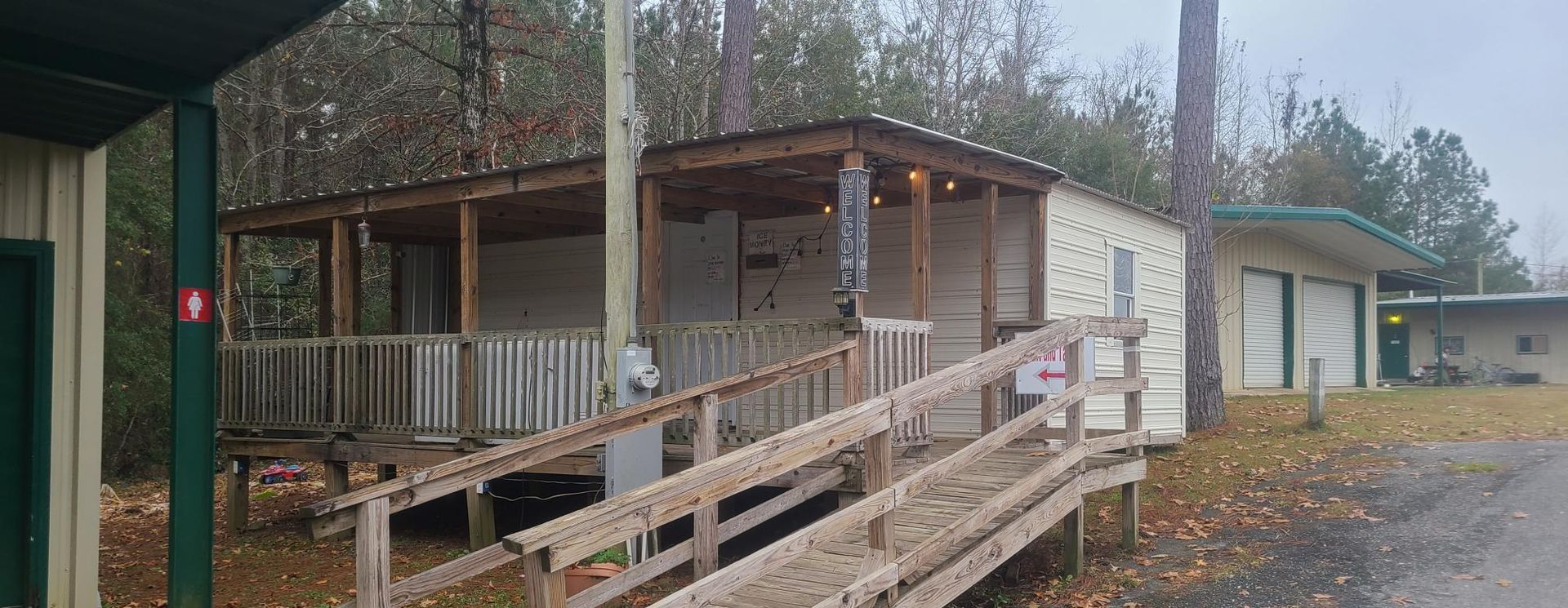 A white house with a tan roof is sitting in the middle of a grassy field.