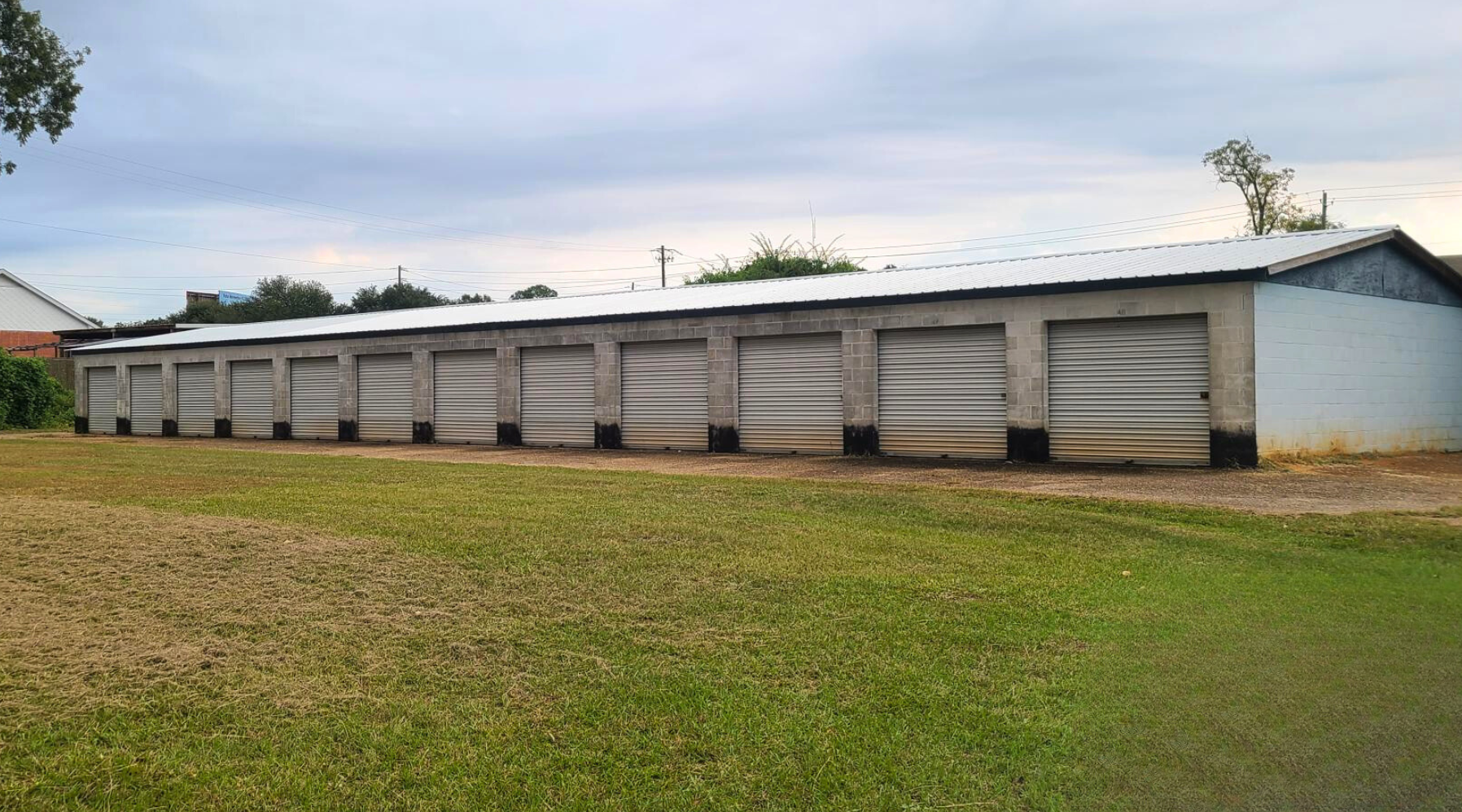 A row of garage doors are lined up in a grassy field.