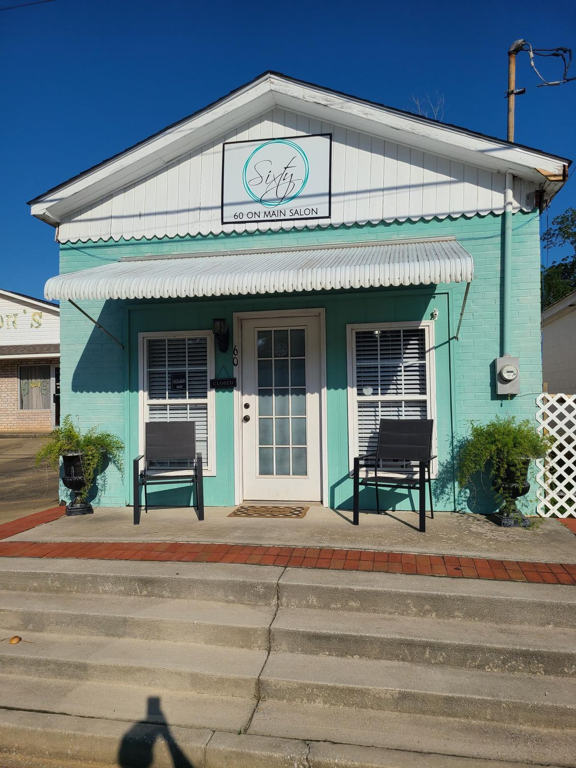 A small green building with two chairs in front of it