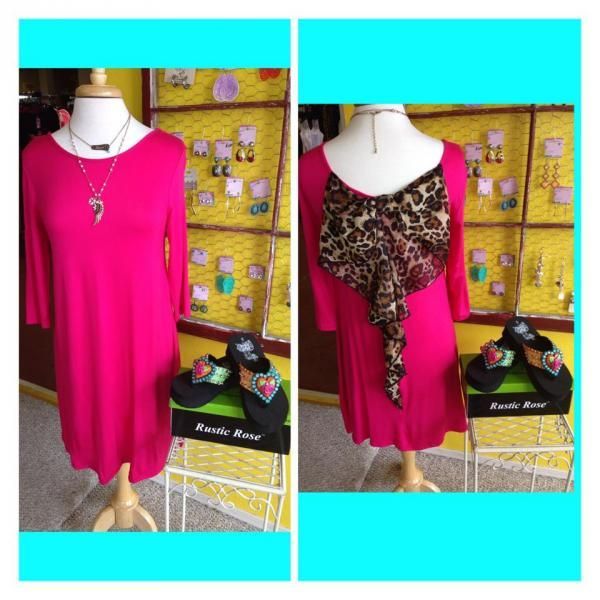Pink dress on a mannequin, shown front and back, with a leopard-print draped back detail against a colorful shop wall