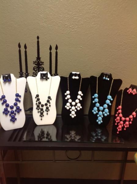 Five necklace displays with purple, black, white, blue, and pink beaded jewelry on a dark table