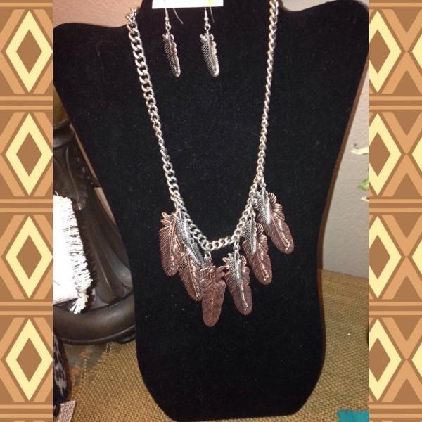 Silver necklace and earrings displayed on a black bust stand against a patterned background.