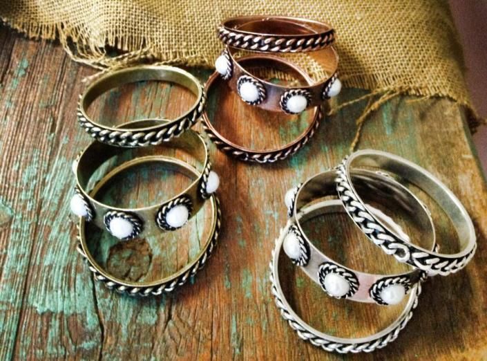 Assorted silver and copper rings with white stones displayed on burlap fabric