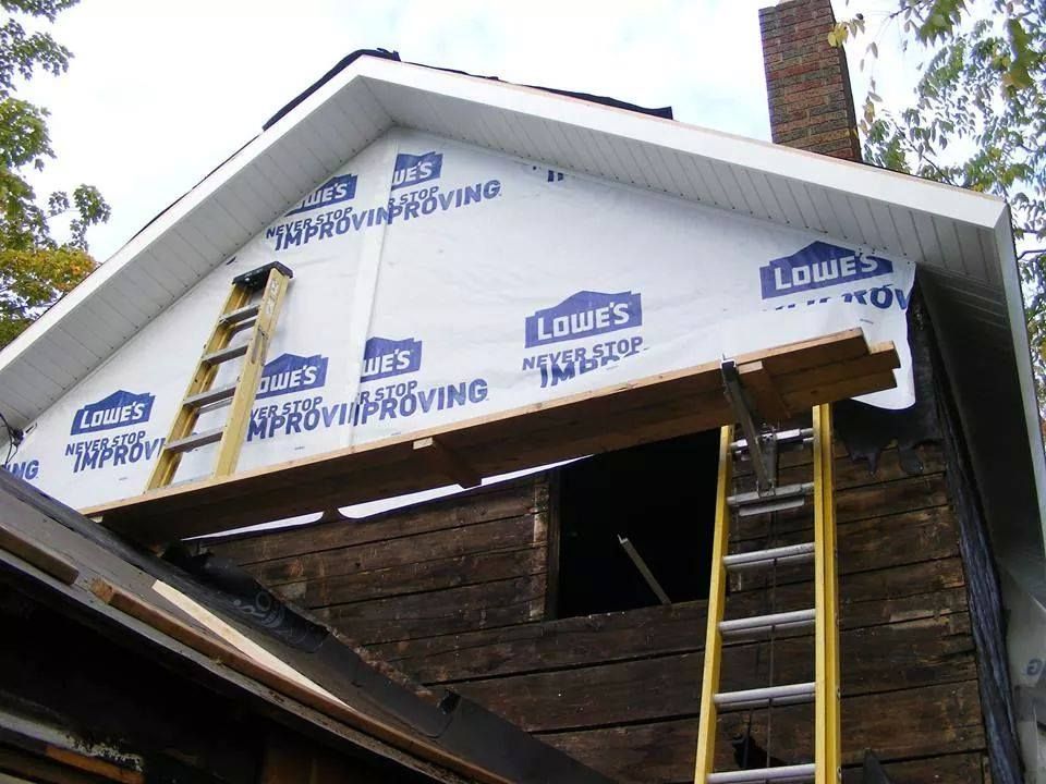 A ladder is attached to the side of a house that is being remodeled