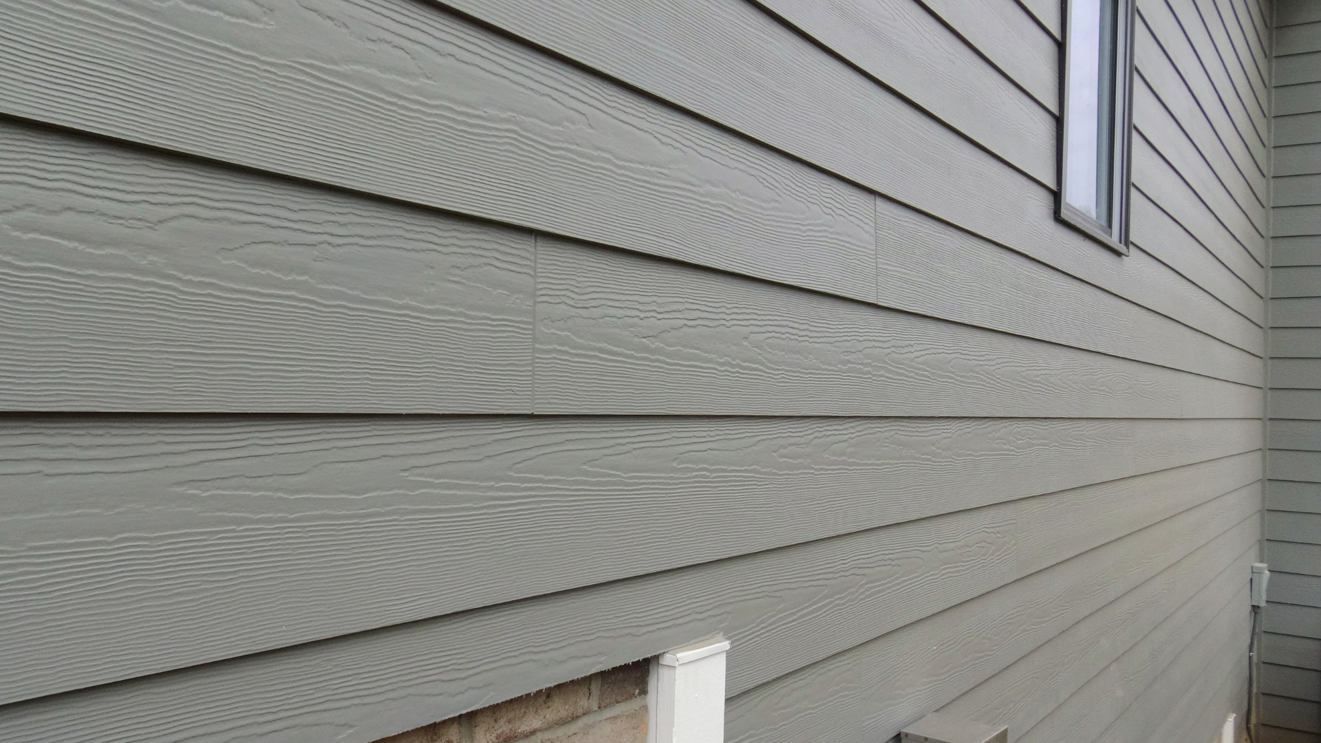 The side of a house with a gray siding and a window.