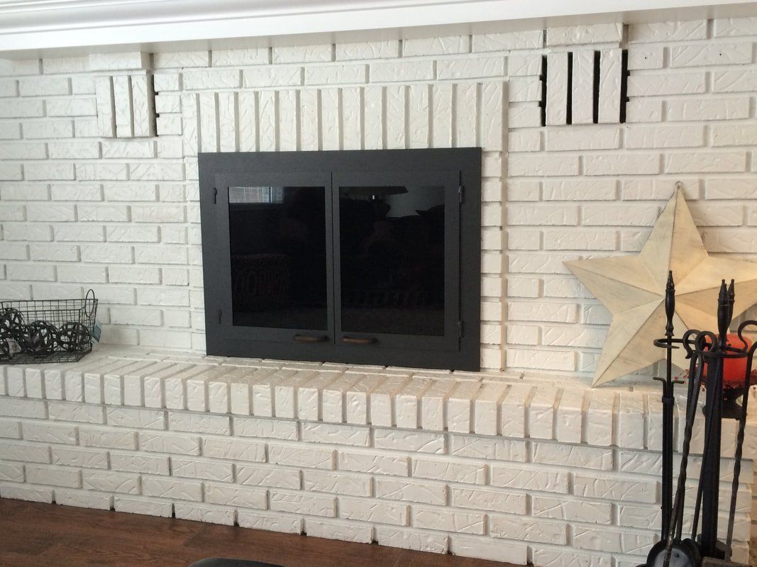 White brick fireplace with black glass firebox, star decor, and tools.