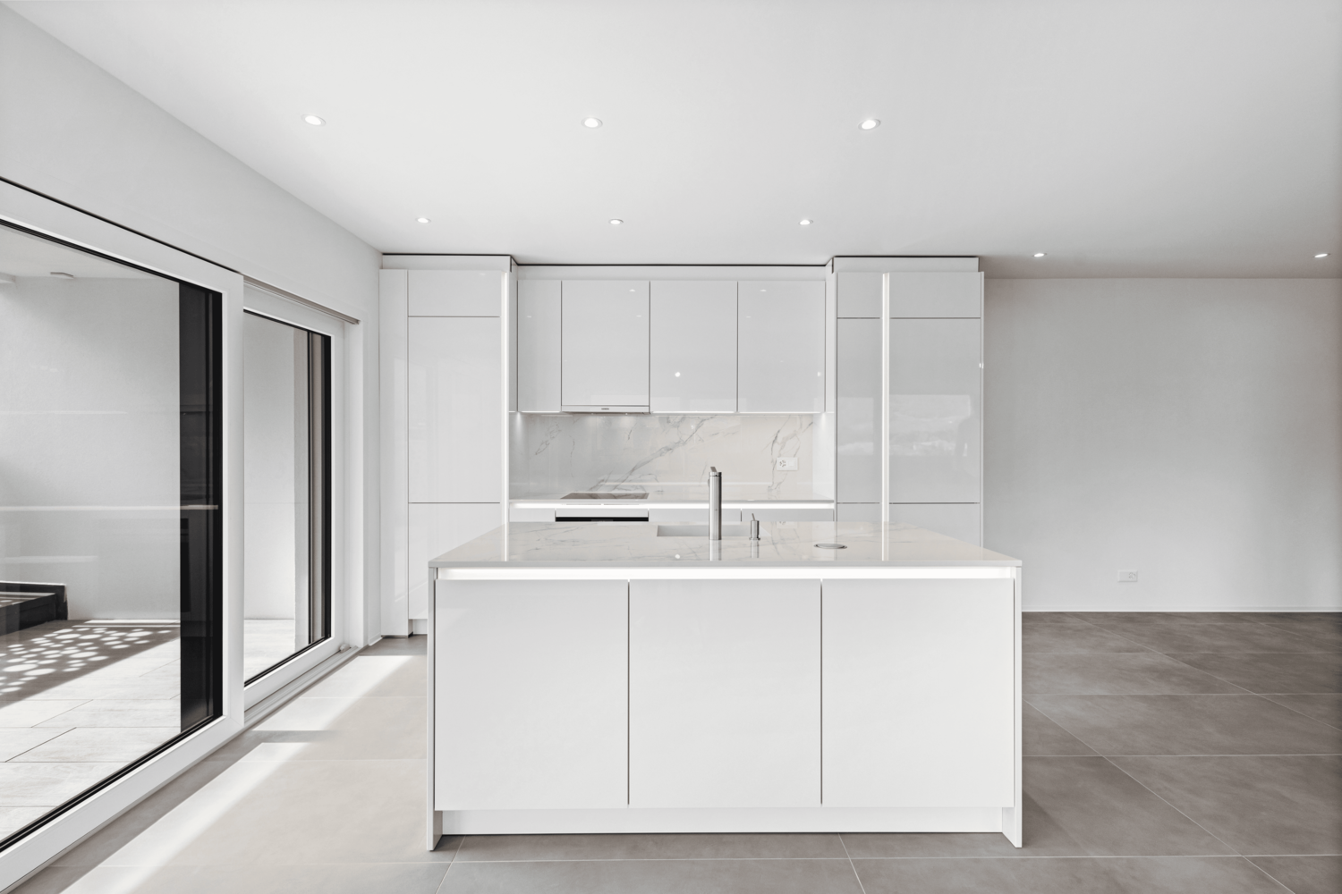 Une cuisine vide avec des armoires blanches et un grand îlot