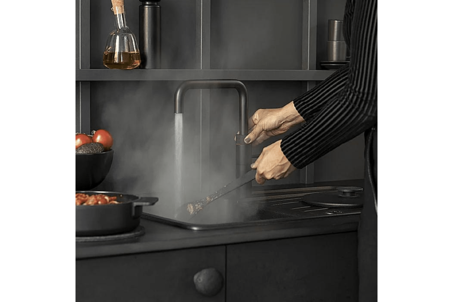 Une personne cuisine dans une cuisine avec de la vapeur sortant du robinet.