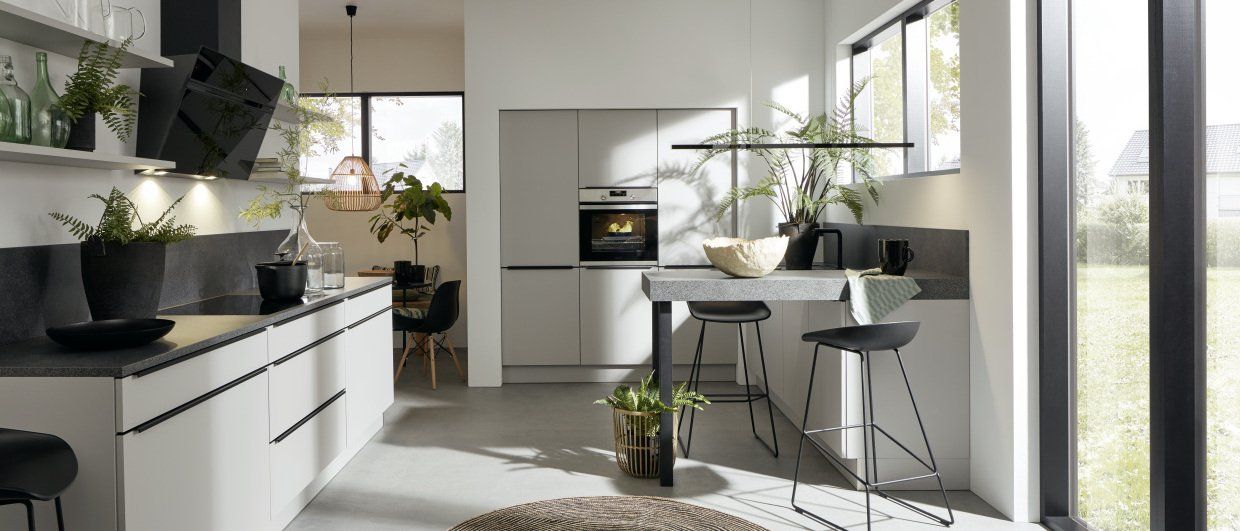 Une cuisine avec des armoires blanches et des appareils électroménagers noirs et une grande fenêtre.