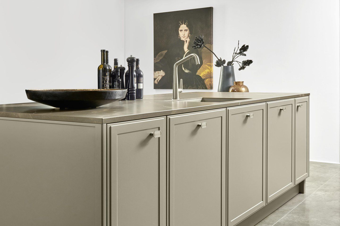 Une cuisine avec un évier, des armoires et un tableau sur le mur.