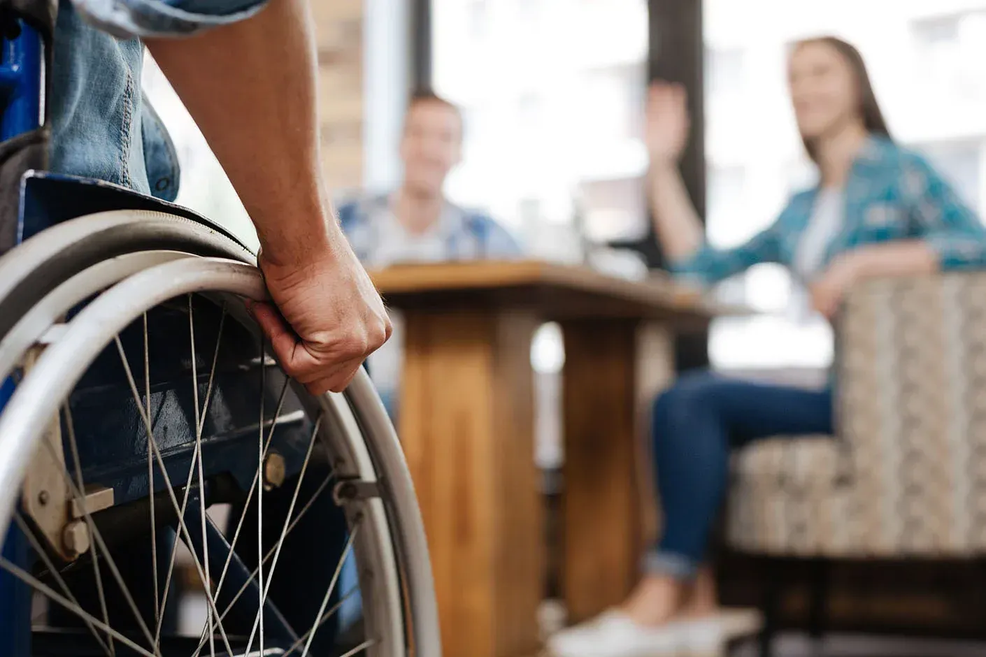 View of a person in a wheelchair being greeted by people inside an office