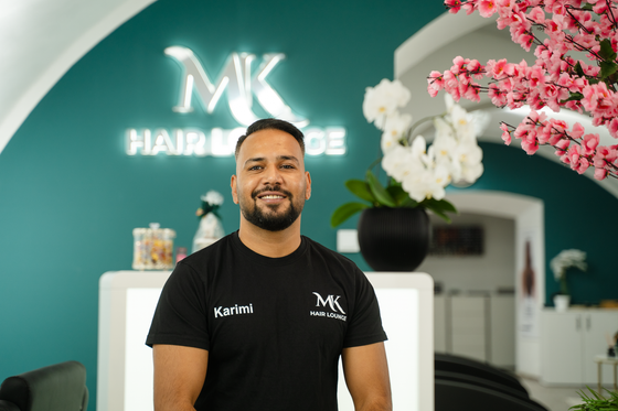 Ein mann steht vor einem schild mit der aufschrift „mk hair & de“.