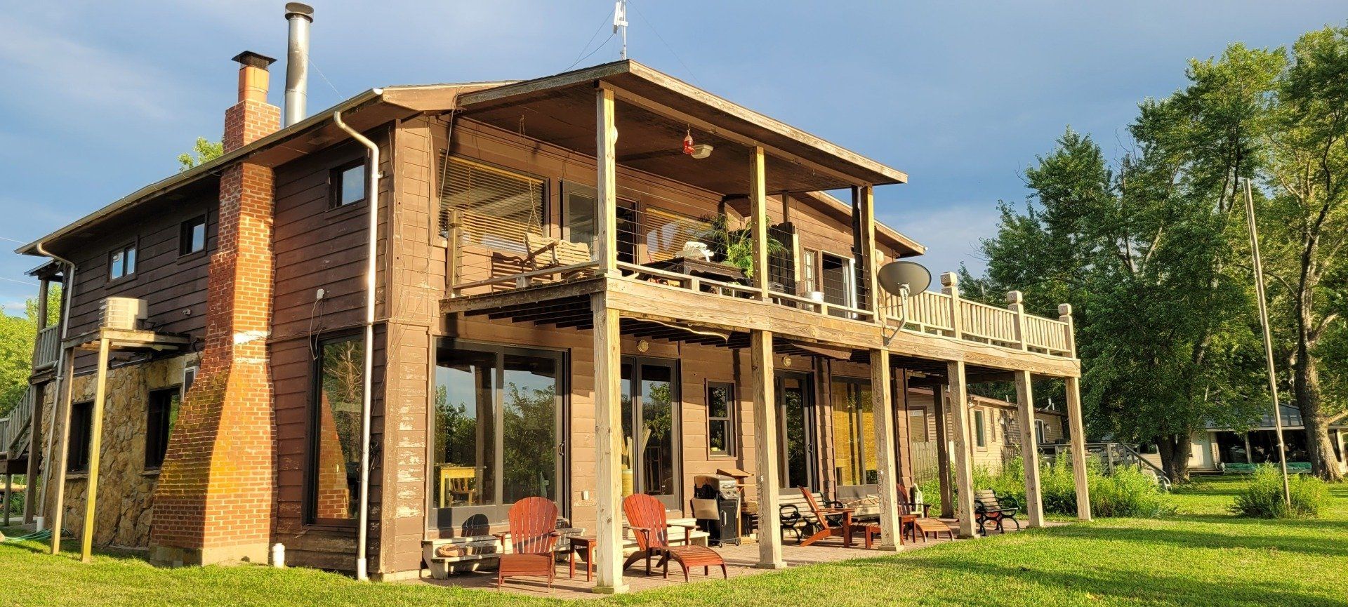 A large house with a lot of windows is sitting on top of a lush green field.