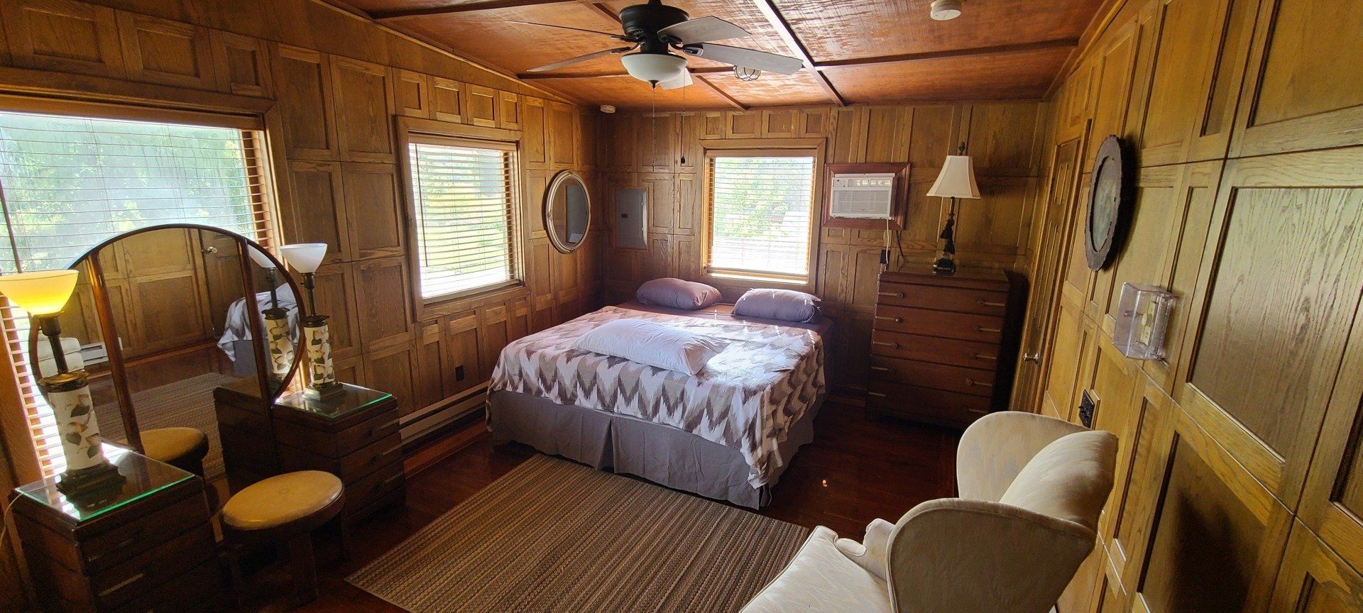 A bedroom with a bed , dresser , chair and mirror.