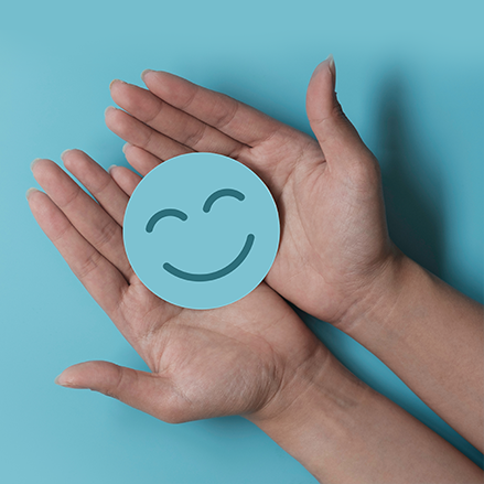 a person is holding a paper smiley face in their hands