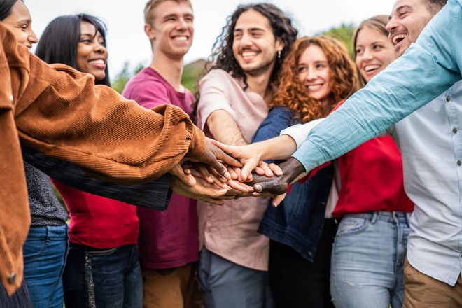 a group of young people are putting their hands together