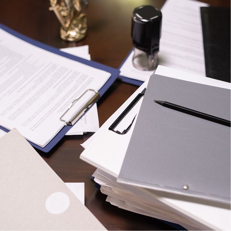 A stack of papers and a pen on a desk
