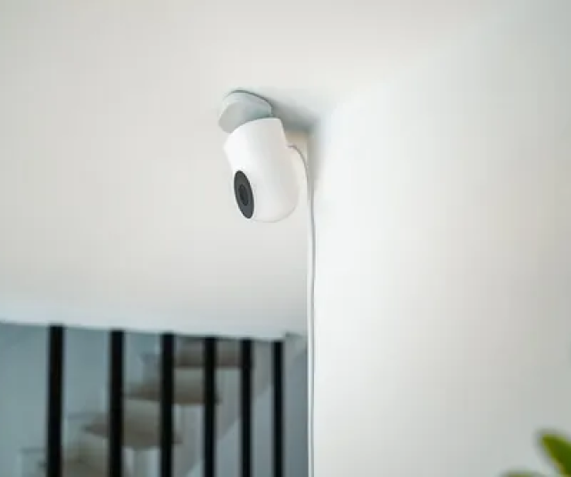 A security camera is mounted on a white wall in a living room.