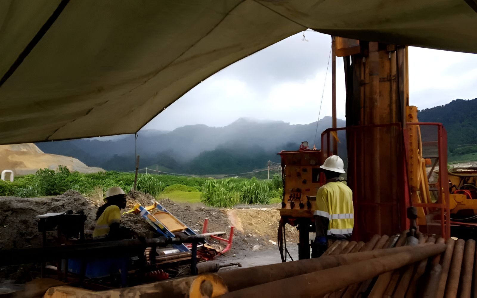 A Man Is Working On A Machine In A Field With Mountains — PGI North QLD In Cardwell, QLD