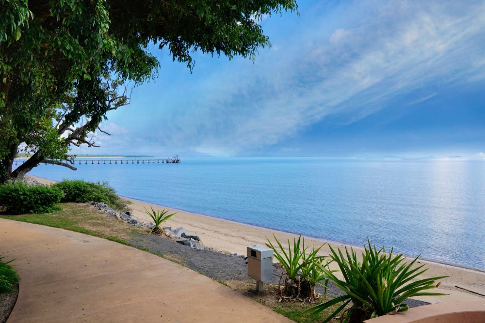 A Path Leading To A Beach With A Pier In The Distance — PGI North QLD In Cardwell, QLD