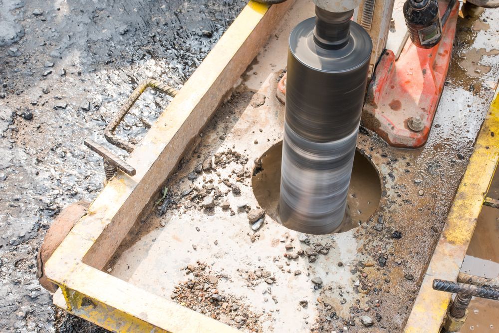 A Person Is Using A Machine To Drill A Hole In The Ground — PGI North QLD In Charters Towers, QLD