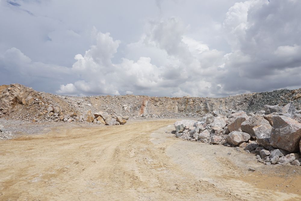 A Dirt Road Leading To A Large Pile Of Rocks In A Quarry — PGI North QLD In Rosslea, QLD