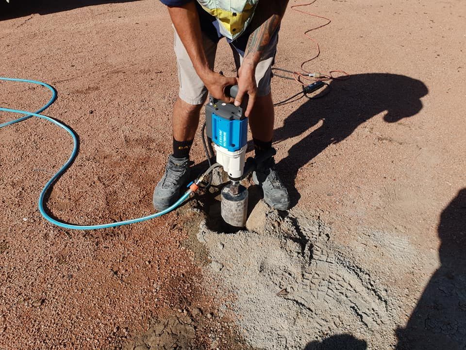 A Man Is Using A Machine To Dig A Hole In The Ground — PGI North QLD In Charters Towers, QLD