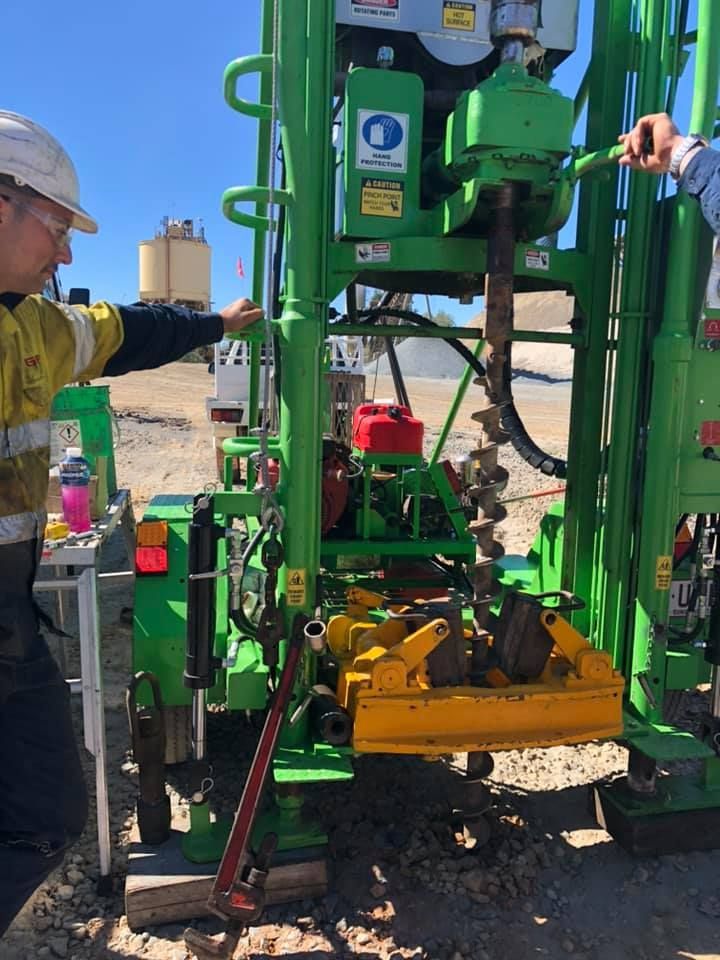 A Man Is Working On A Green And Yellow Drilling Machine — PGI North QLD In Charters Towers, QLD