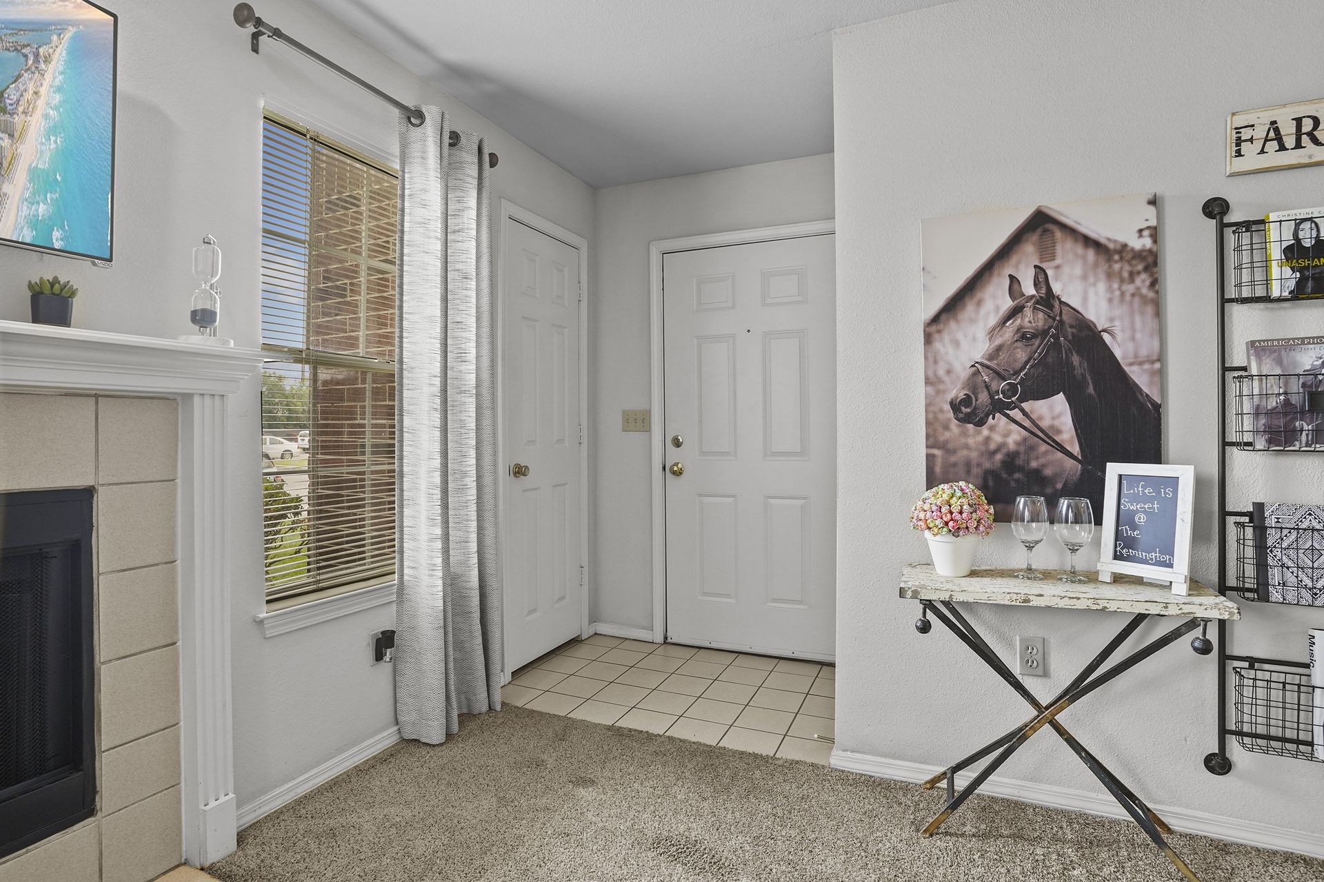 A living room with a fireplace and a painting of a horse on the wall.