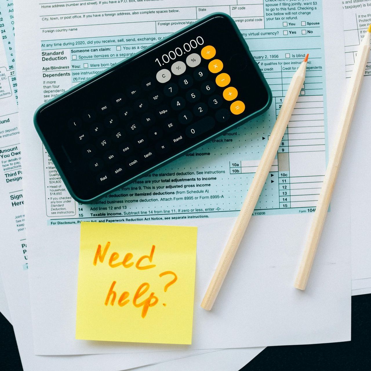 A calculator and a sticky note that says need help